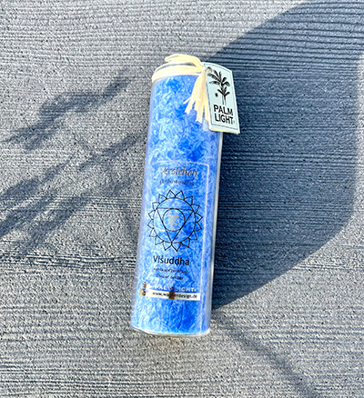 Blaue Halschakra Kerze Visuddha im Freien mit Pflanzenschatten