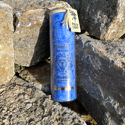 Hellblaue Visuddha Chakra Kerze auf Steinen im Freien