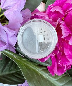 Geöffneter Dark Grey Matt Mineral Eyeshadow von Angel Minerals zwischen Blüten