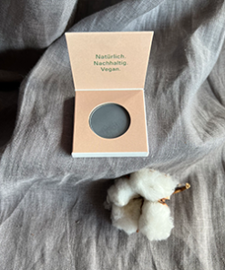 Geöffneter Dark Grey Eyeshadow von Angel Minerals neben Baumwollzweig