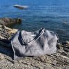 Grau mellierte Strandtasche aus Ökotex Leinen, im Hintergrund Meer