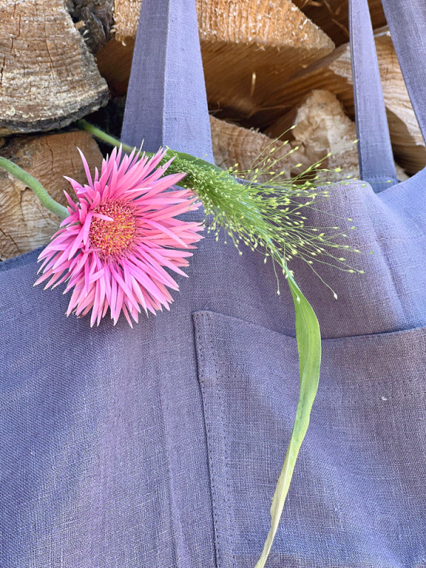 Detailaufnahme pastell lila Strandtasche mit Blumen aus Ökotex Leinen von Linen Couture vor Holz hängend