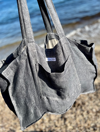 Graue Leinen Strandtasche frei hängend vor dem Meer