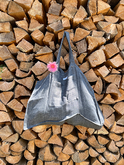 Leinen Strandtasche Asphalt Grau vor einem Holzstapel