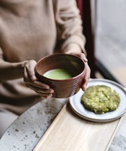Person hält Matchaschale mit grünem Matcha und Matcha-Gebäck