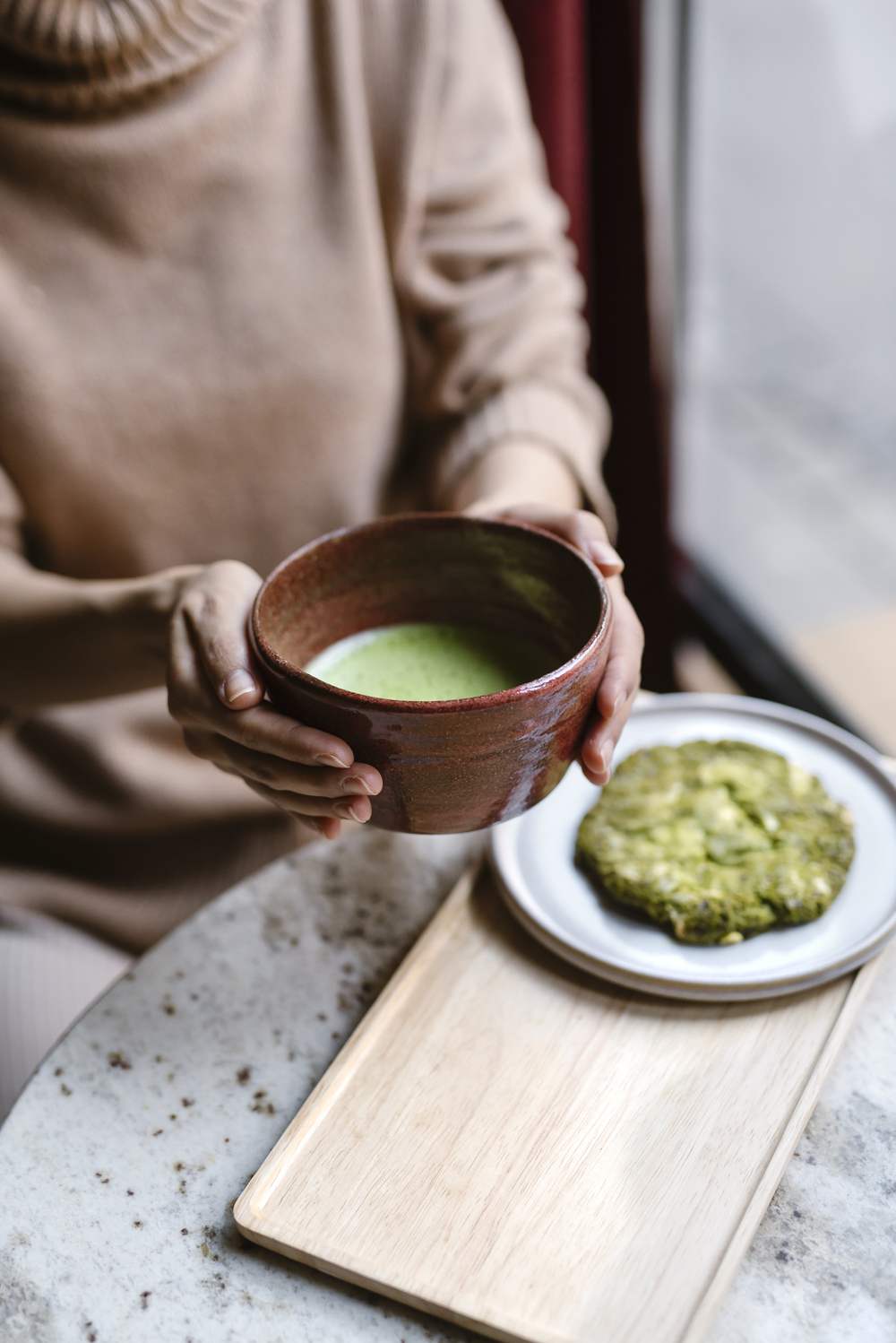 Person hält Matchaschale mit grünem Matcha und Matcha-Gebäck