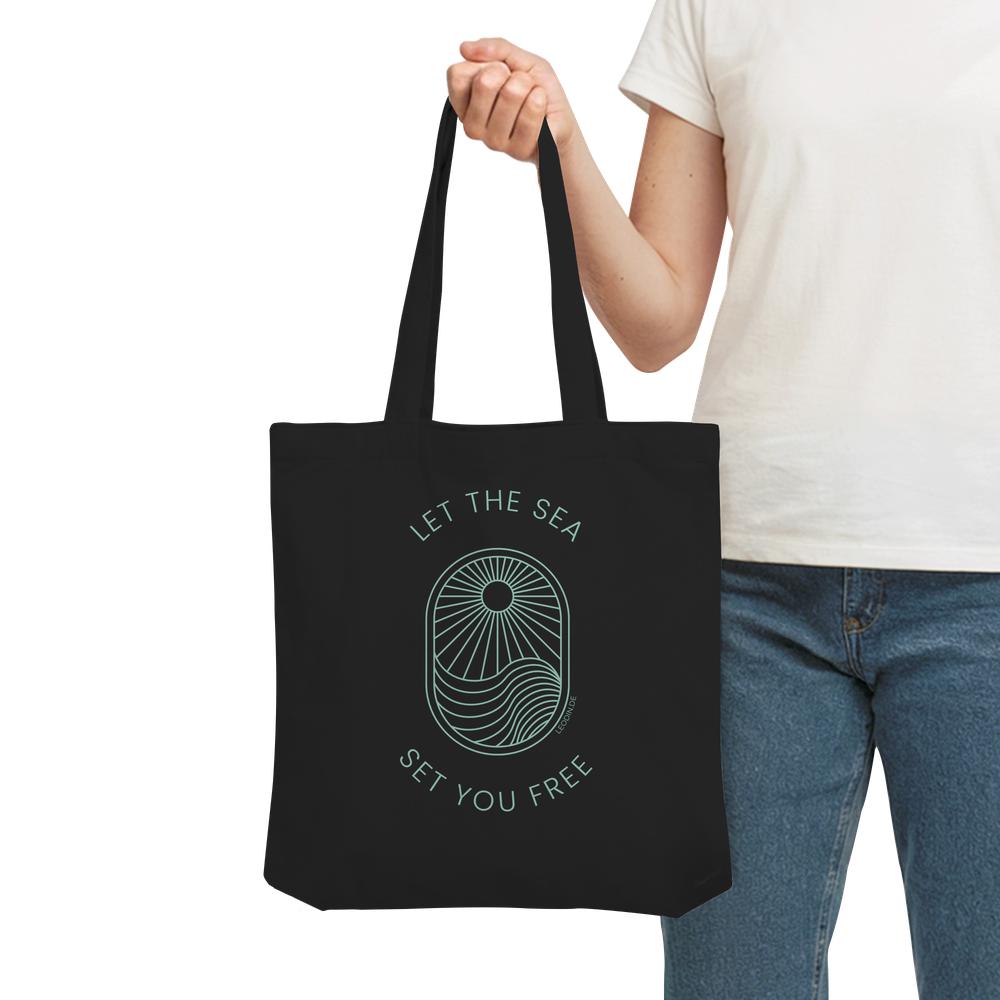 Frau trägt schwarze Meer Tote Bag mit Wellenmotiv