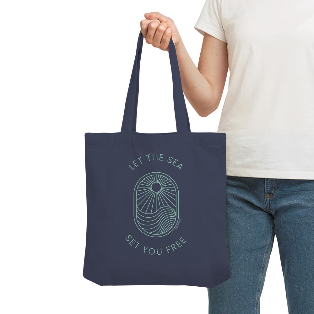 Frau trägt dunkelblaue Meer Tote Bag mit Wellenmotiv